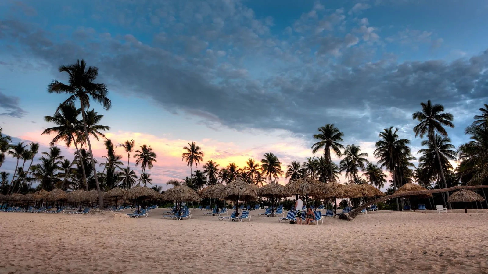 Atardecer en la playa de Bávaro, Punta Cana, con palmeras, sombrillas de cana y tumbonas sobre la arena