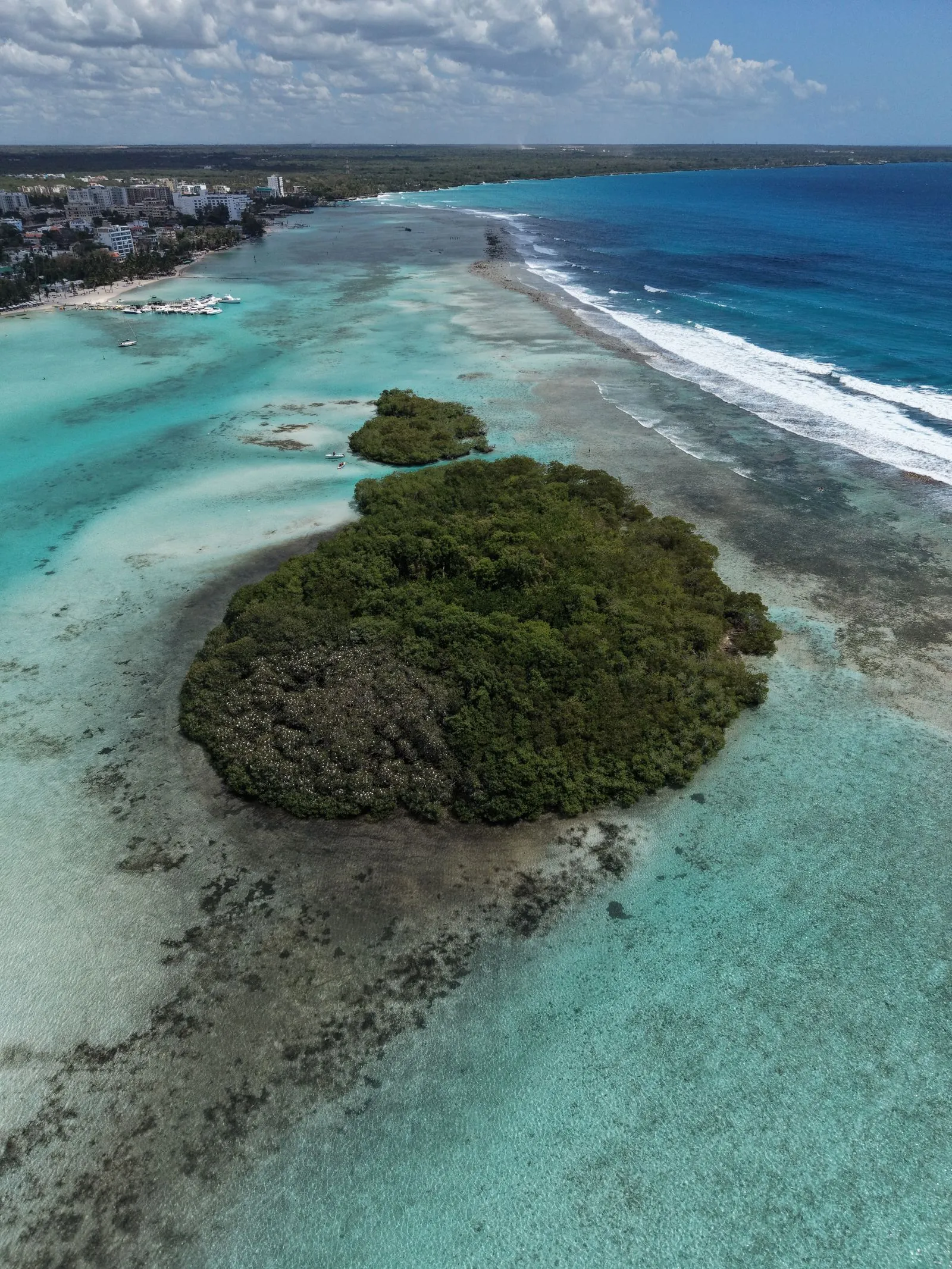 Vista aérea de la playa Boca Chica con su laguna de agua turquesa, el arrecife de coral y un islote de manglar