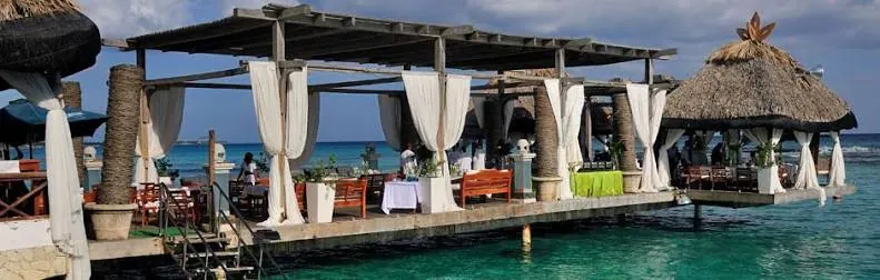 Muelle de madera de Boca Marina sobre el mar de Boca Chica, con cortinas blancas, ranchos y mesas