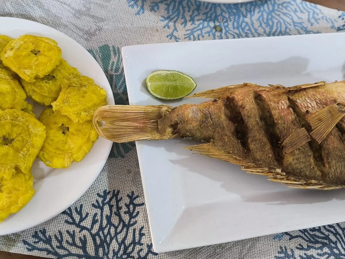 Pescado frito entero con limón y un plato de tostones en el restaurante Buxeda de Boca Chica