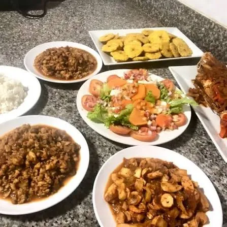 Mesa con varios platos de Buxeda: arroz, carnes guisadas, ensalada, tostones y pescado