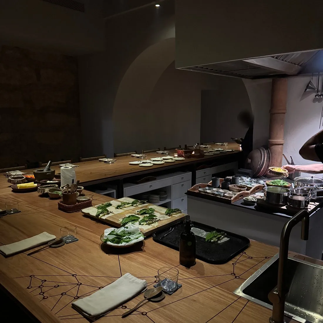 Barra de madera de Casarré alrededor de la cocina abierta, con platos de cerámica e ingredientes locales