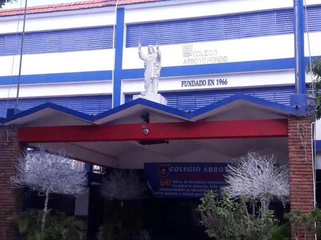 Entrada del Colegio Arroyo Hondo en Santo Domingo, edificio blanco y azul con la estatua del Sagrado Corazón | El Colegio Arroyo Hondo, fundado en 1966, es uno de los más antiguos de la zona. | Colegio Arroyo Hondo