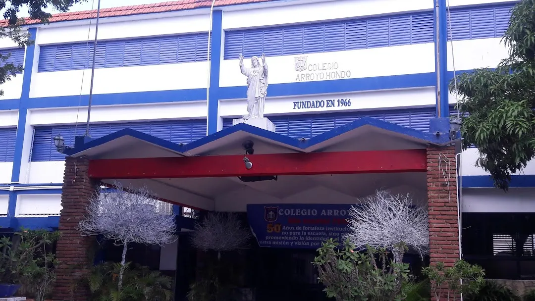 Fachada del Colegio Arroyo Hondo en Santo Domingo, con la estatua del Sagrado Corazón y el letrero «Fundado en 1966»