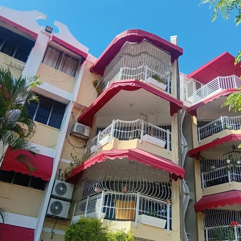 Edificio familiar de cuatro niveles con balcones enrejados y toldos rojos en La Esperilla, Santo Domingo