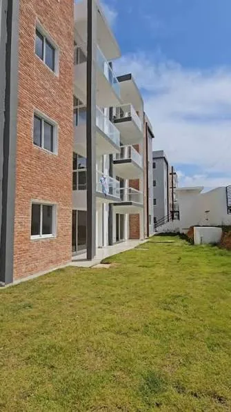 Fachada lateral de ladrillo y área verde de Parque de las Colinas II