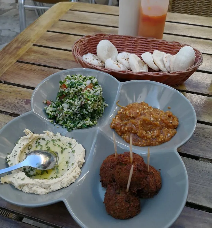 Plato de falafel con hummus, tabulé y baba ganush y una cesta de pan árabe
