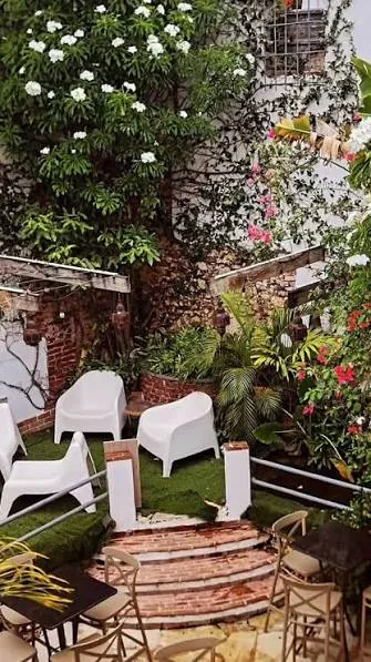 Terraza con jardín y sillas blancas de Falafel Zona Colonial