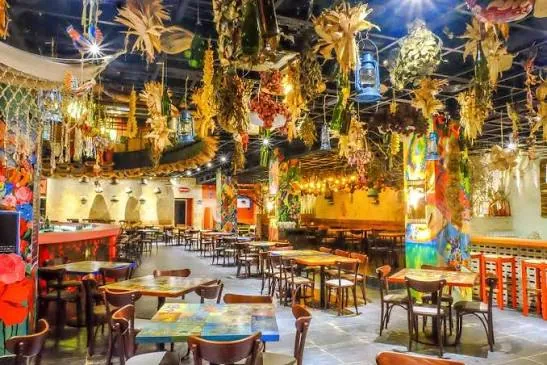 Salón interior de Jalao con decoración colorida de flores y artesanías dominicanas en el techo