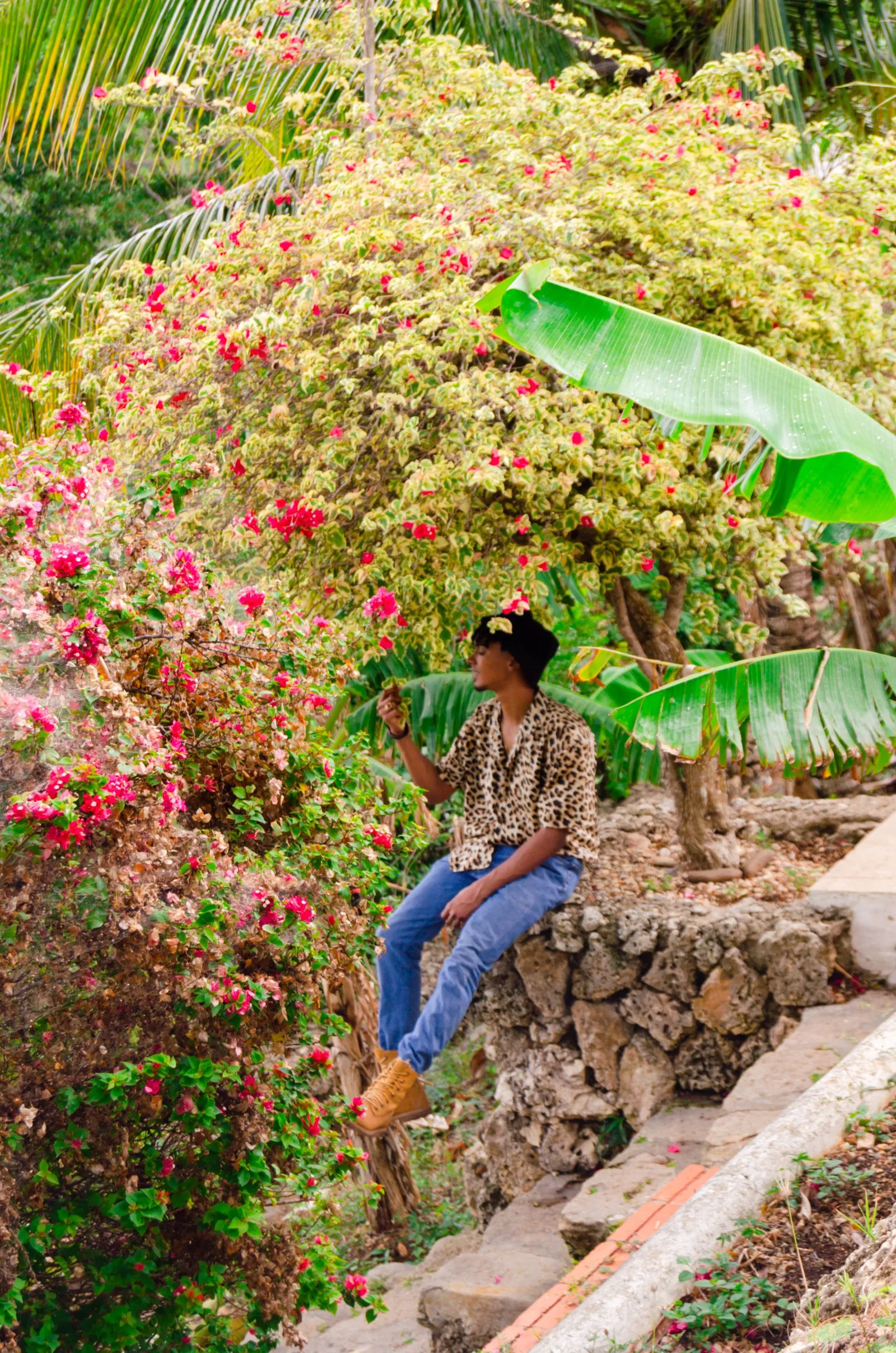 Visitante sentado entre flores y escalinatas de piedra en un jardín tropical de La Romana, República Dominicana