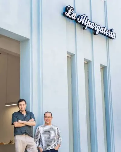 Los dueños de La Alpargatería frente a la fachada con el letrero del negocio, en la Zona Colonial