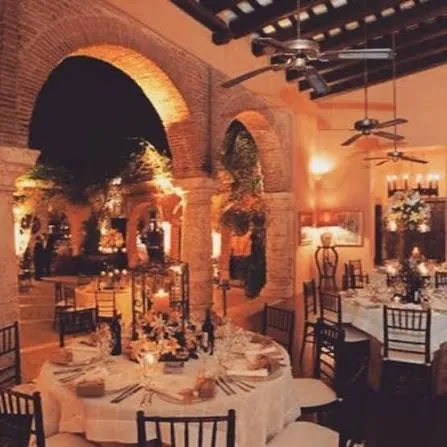 Salón de La Briciola con arcos de ladrillo y mesas redondas con mantel blanco