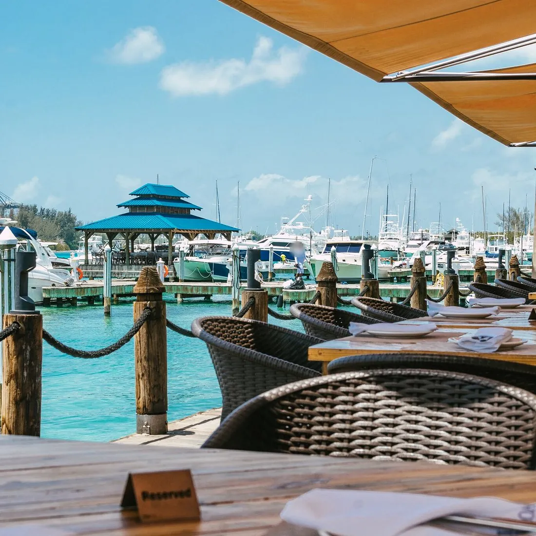 Terraza de La Proa Bistro Marino con mesas de madera frente a los muelles y yates de la marina de Andrés