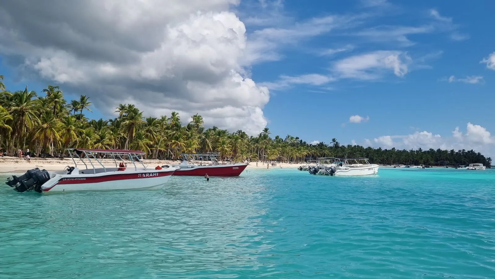 Lanchas de excursión ancladas frente a una playa de arena blanca en la costa de La Romana, República Dominicana