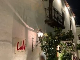 Letrero de Lulú Tasting Bar en una fachada colonial de noche, con farol y balcón de hierro