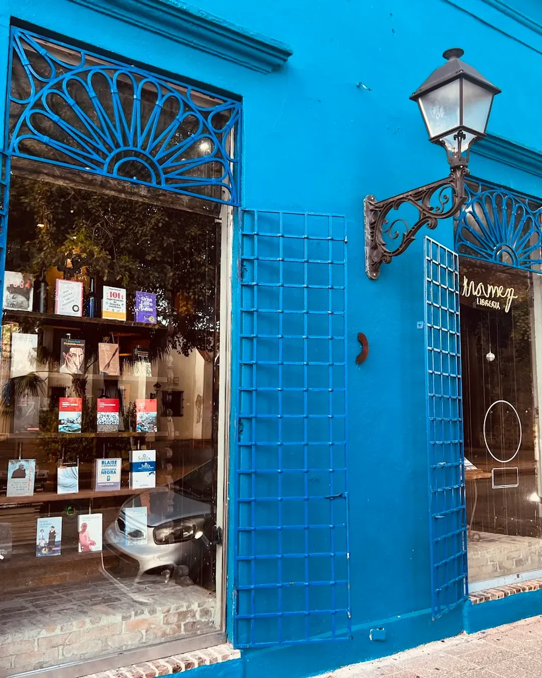 Fachada azul de Mamey Librería Café, con libros en la vitrina y un farol colonial, en la Zona Colonial de Santo Domingo