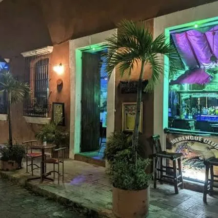 Fachada de Merengue Club de noche en la calle Hostos, con luces verdes y mesas en la acera, Zona Colonial