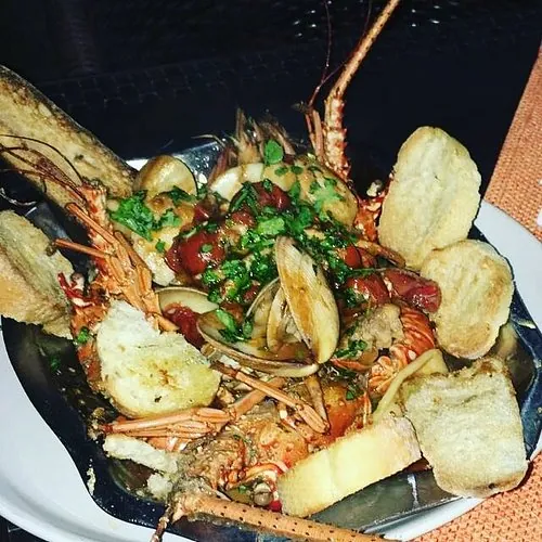 Plato de langosta con almejas, tomate y pan tostado en Momo Paradise, Boca Chica