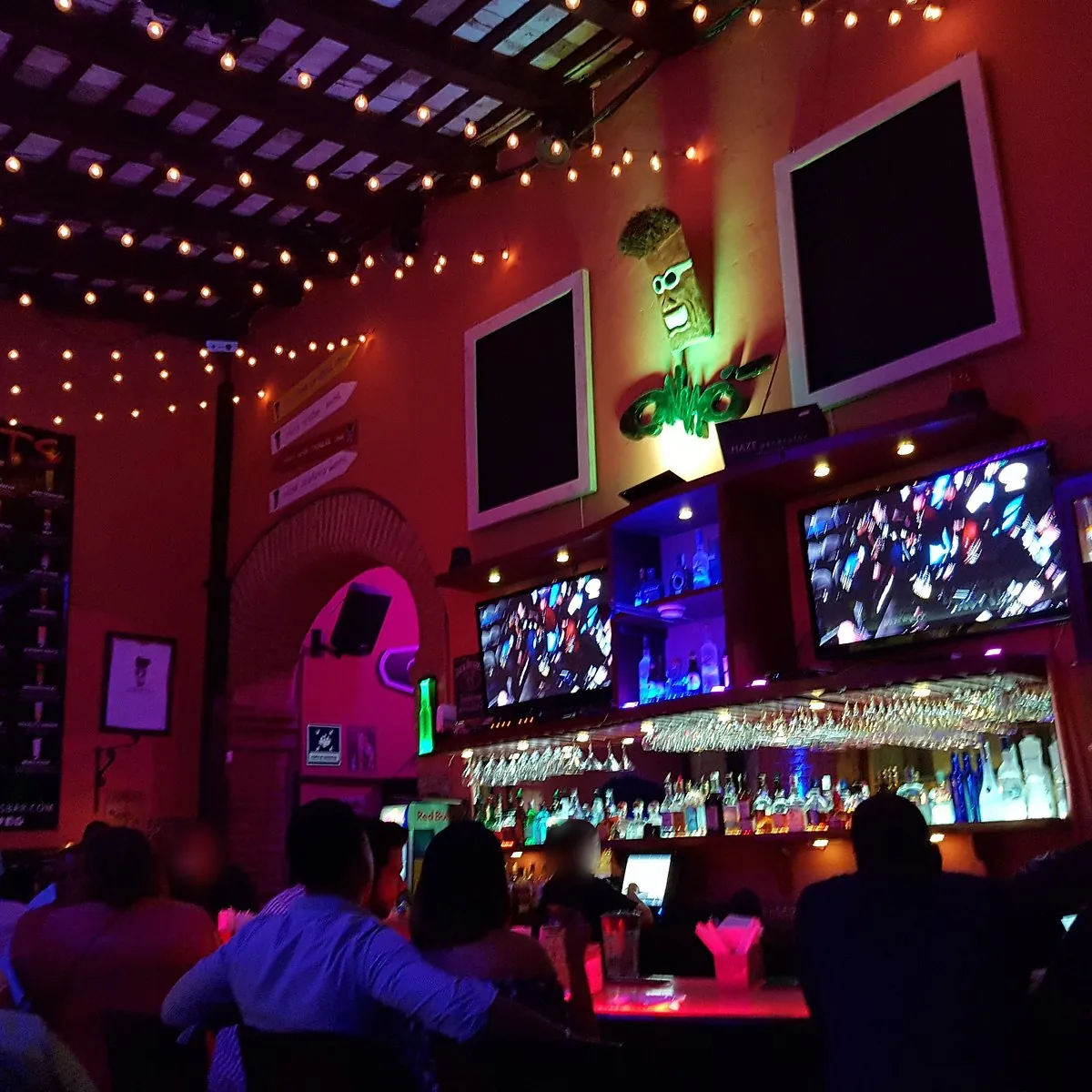 Interior de Onno's en la Zona Colonial de Santo Domingo, con luces colgantes, pantallas y la barra iluminada