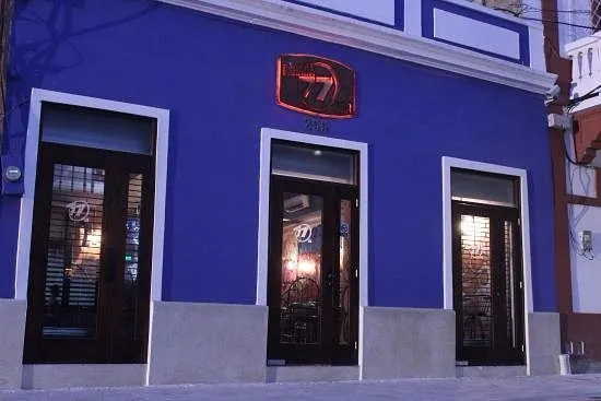Fachada azul de Parada 77 en la calle Isabel la Católica, con su letrero iluminado sobre la puerta, Zona Colonial