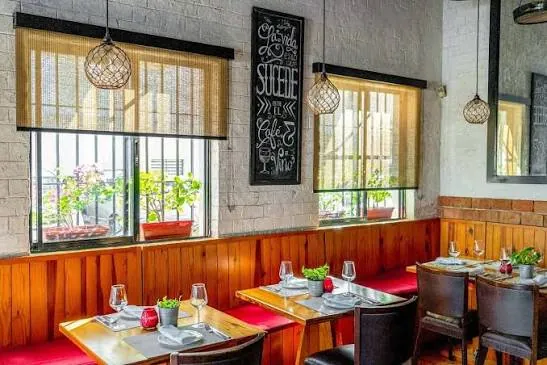 Salón interior de Pura Tasca, con ventanas a la calle, pared de ladrillo blanco y mesas de madera