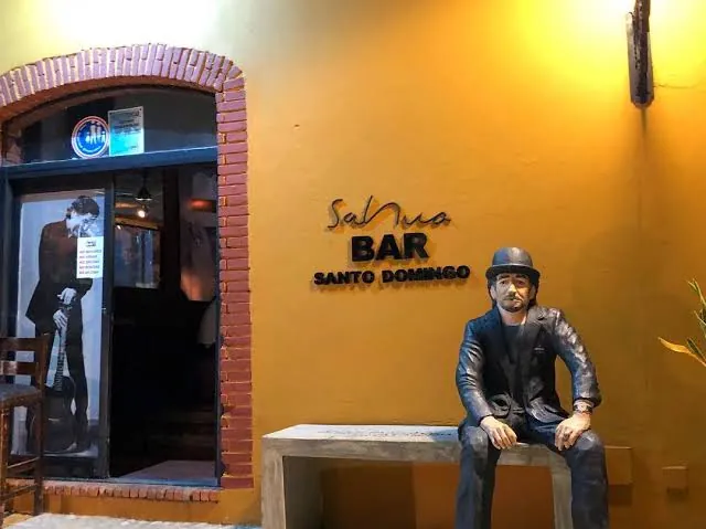 Entrada de Sabina Bar en la calle Isabel la Católica, con una estatua sentada en un banco junto a la puerta
