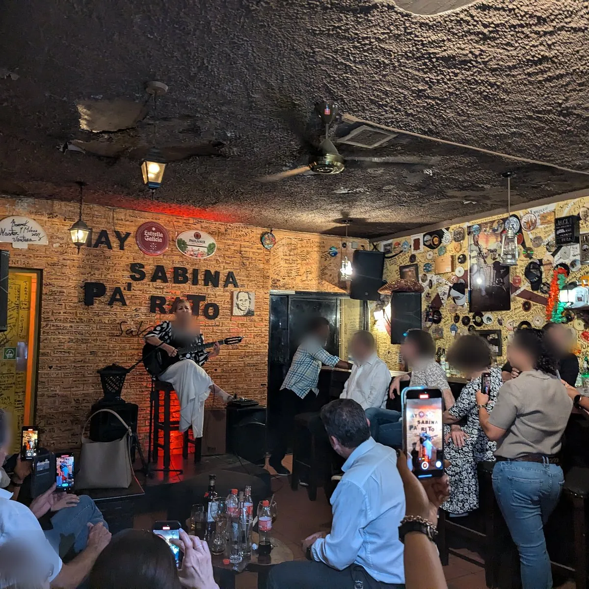 Cantante con guitarra en Sabina Bar, en la Zona Colonial, con el público grabando con sus celulares