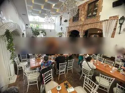 Patio de Santoña Gastro Bar Colonial con candelabros, sillas blancas y paredes de ladrillo