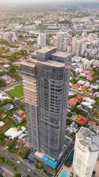 Torre de apartamentos en la avenida Anacaona, con casas, jardines y edificios de Los Cacicazgos alrededor, en Santo Domingo