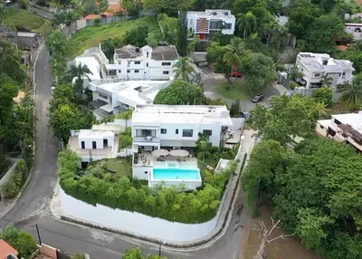 Vista aérea de casas con piscina y jardines entre árboles en Arroyo Hondo, Santo Domingo